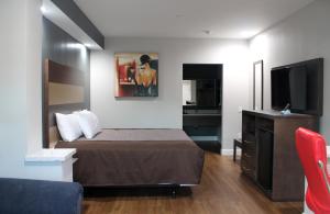休斯顿Grand Villa Inn and Suites Westchase/Chinatown的配有一张床和一台平面电视的酒店客房