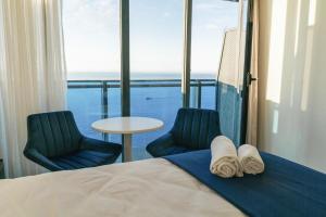 巴统Orbi Hotel Batumi City的一间卧室配有一张床、两把椅子和一张桌子