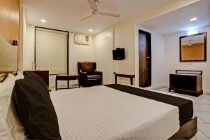 SaravliSuper OYO Flagship Hotel Golden Nest的一间卧室配有一张床、一张桌子和一把椅子