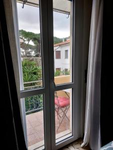 比萨MIGU POINT Pisa的一间设有窗户的房间,外面设有红色椅子