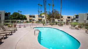 斯科茨Updated Condo in A Old Town Scottsdale Location的庭院内的游泳池,庭院内种有长椅和棕榈树