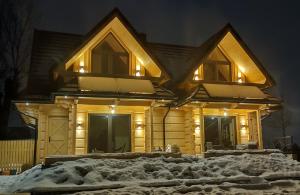 穆扎希赫尔Domki Hygge Tatra Luxury Chalet的一堆积雪上灯火的木屋