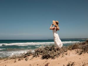 Narbolia伊斯阿里纳斯度假酒店的站在海滩上身着白色衣服的女人