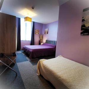 Saint-SavinienLogis Hôtel & Restaurant Le Saint Savinien的紫色卧室设有两张床和一扇窗户