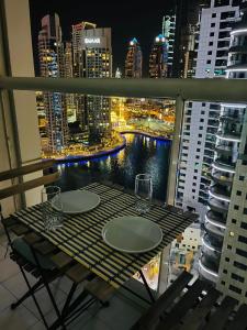 迪拜Amazing 1 bedroom apt in Marina的晚间在阳台上摆放着酒杯的桌子
