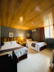 佩诺诺梅Hotel Guacamaya的一间卧室设有两张床和木制天花板