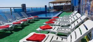 科威特Blue Waves Abu Halifa أمواج الخليج الزرقاء的游泳池旁一排带红色靠垫的白色椅子
