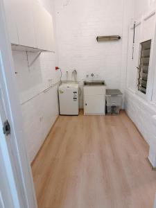 悉尼three bedroom house within walking distance to light rail station的厨房拥有白色的墙壁和木地板
