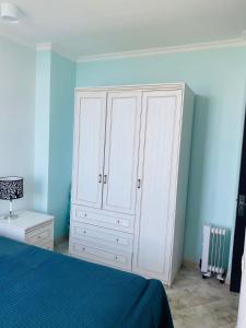 马钦加里Zura's Guest House的卧室配有白色橱柜和蓝色的墙壁