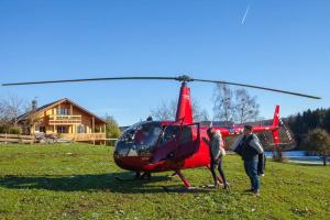 MollenbergFerienhaus Alpenpanorama Chalet的两人站在红色直升机旁边