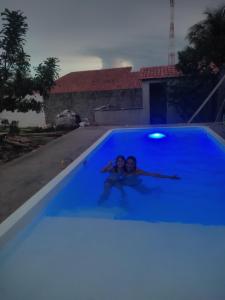 帕拉库鲁Pousada Vista Verde的两个孩子在游泳池里,灯光蓝色