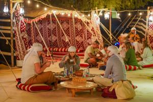 迪拜Al Marmoom Oasis “Luxury Camping & Bedouin Experience”的一群坐在地板上吃食物的人
