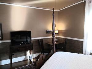 罗阿诺Black Lantern Inn的一间卧室配有一张床、一台电视和一张桌子