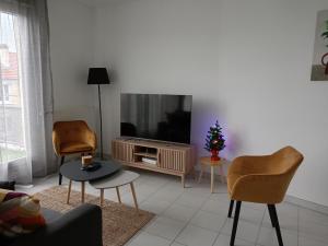 圣吉欧梅斯Superbe appartement ,6 pers, proche de Paris, dans résidence privée , parking et WIFI gratuits! !的客厅配有两把椅子和电视