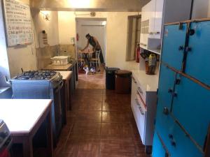 皮萨克Intihuatana Hostel的一间厨房,内配蓝色橱柜,后面有一个人