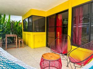 别霍港Casitas Coloradas Puerto Viejo的一个带椅子和桌子的门廊和一座黄色的建筑