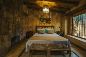 蒂尔卡拉卡瓦尼亚斯阿加坎托山林小屋的一间卧室设有一张大床和石墙