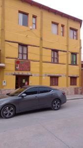 蒂尔卡拉Hotel El Jardin Dante的停在黄色建筑前面的灰色汽车