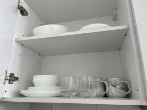 雪邦horizon suite 25-11的白色的橱柜,有盘子,碗和玻璃杯