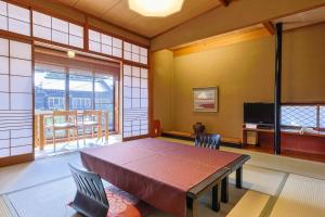 丰冈市城崎山本屋的一间带桌子和电视的用餐室