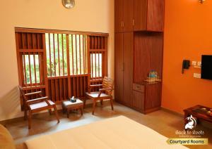 Kizhake ChālakudiBack to Roots Ayurveda Retreat的客厅设有两把椅子和橙色墙壁