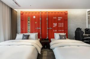 金浦Gimpo JK Hotel的红色门的房间里设有两张床
