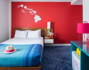 檀香山Shoreline Hotel Waikiki的红色卧室,配有带帽子的床