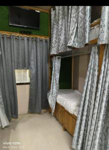 瓦拉纳西Shree Madhvam AC Dormitory的客房内的双层床配有窗帘和电视