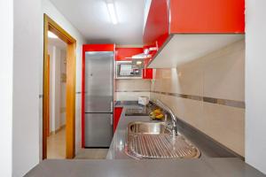 罗萨里奥港Puerto Playa 2的厨房配有不锈钢水槽和红色橱柜