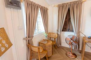 Ban Wat TanNakhao Cottage的客房设有2扇窗户和桌椅。
