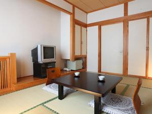 松本中之汤温泉传统日式旅馆的客厅配有桌子和电视