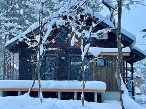 白马村The Misorano Cottage的两棵树前的雪覆盖的房子