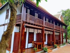 琅勃拉邦Villa Kee Lee Hotel 1的一座带木阳台、桌子和树的建筑