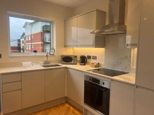 里克曼斯沃斯New build 1 bedroom modern apartment Rickmansworth的厨房配有白色橱柜、水槽和窗户。