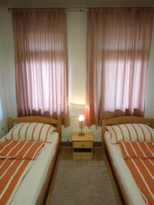 图兹拉Apartment and rooms"Tabašnice"Tuzla centar的一间卧室配有两张床和一张带台灯的桌子