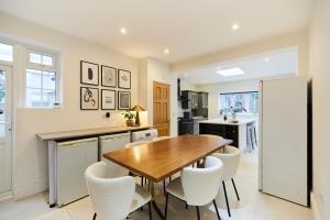 伦敦The Redbridge Sanctuary - Spacious 3BDR House with Garden的厨房配有木桌和白色椅子