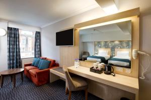 伦敦Bedford Hotel的酒店客房配有一张床和一张带镜子的书桌
