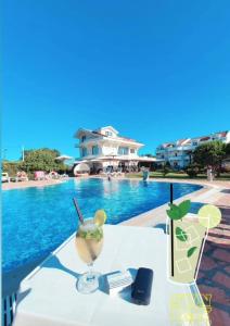 东吉托伊Hotel Comfort & Villas的游泳池畔的桌子和饮料