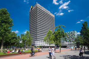 乌得勒支Beautiful apartment in vibrant Utrecht City Center的一座高大的建筑,人们在公园里骑着自行车