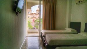 科罗萨尔Del Parque Hotel的客房设有三张床、一台电视和一扇窗户。