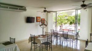科罗萨尔Del Parque Hotel的一间带桌椅和电视的用餐室
