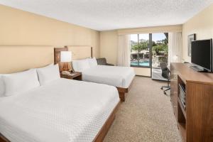 迈尔斯堡Doubletree by Hilton Fort Myers at Bell Tower Shops的酒店客房设有两张床和电视。