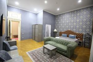 巴库Pilot Baku hotel的一间卧室配有绿色沙发、一张床和一张桌子