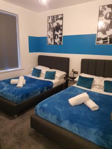 达德利Tudors eSuites Three Bedroom House with Private Garden的蓝色和白色的客房内的两张床
