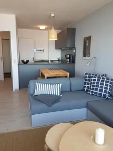 达默Strandhotel Wohnung 62的一间带蓝色沙发的客厅和一间厨房