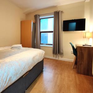 利物浦Liverpool City Centre Private Rooms including smart TVs - with Shared Bathroom的一间卧室设有一张床、一台电视和一个窗口。