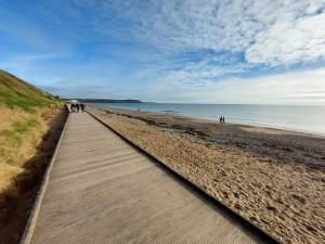 约尔Happy Sandy Feet - Modern, Cozy & Warm Holiday Home with Lovely Sea Views in Youghal`s Heart - Top-Notch Electric Heaters - Long Term Price Cuts的海滩上的木板路,人们在海滩上散步