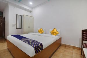 海得拉巴SPOT ON Apsara Hotel的一间卧室配有一张大床,提供黄色和蓝色的枕头