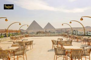 开罗New Comfort Inn Giza的餐厅设有桌椅,以金字塔为背景