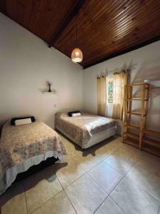 戈亚斯州上帕莱索Casa Amarela - Aconchegante e Familiar的一间卧室设有两张床和木制天花板